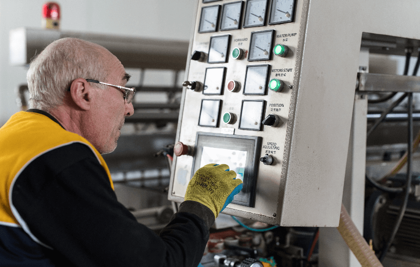 Un homme en gants jaunes travaille sur une machine.